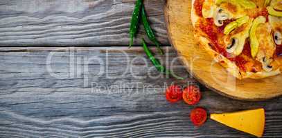 Pizza by tomatoes and chili peppers on table