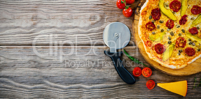 Pizza on by cutter on wooden table