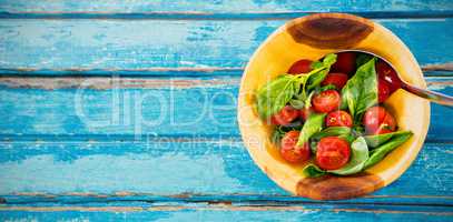 Fresh salad with spoon in wooden bowl on table
