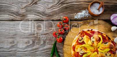 Pizza by spices on wooden table