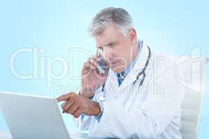 Composite 3d image of male doctor pointing at laptop while using mobile phone