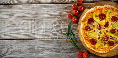 Pizza by tomatoes on wooden table
