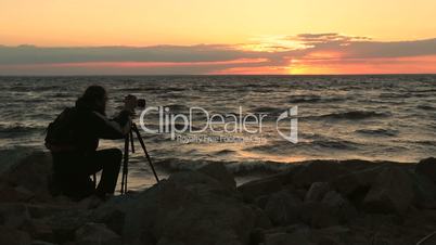 Photographer taking photos of seascape at sunset