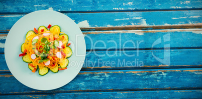 Fresh salad in circle plate on wooden table