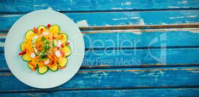 Fresh salad in circle plate on wooden table