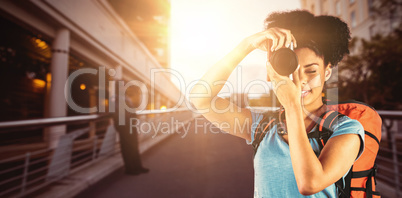 Composite image of young woman with backpack taking picture