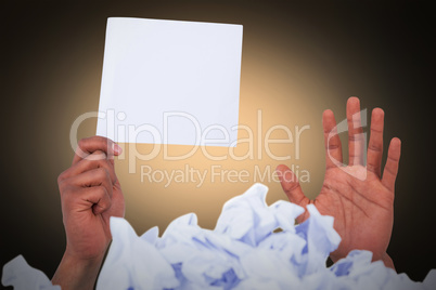 Composite image of heap of crumpled paper with hand holding blank page