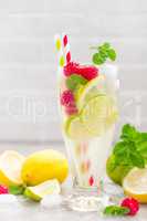 Lemon mojito cocktail with lime, mint and raspberry, cold drink with ice.