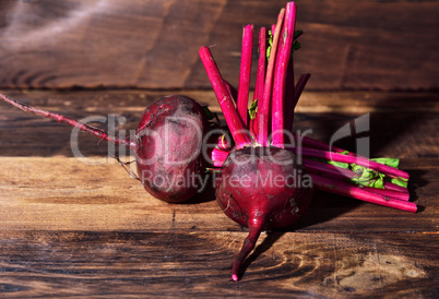 Two fresh beets on a brown wooden background