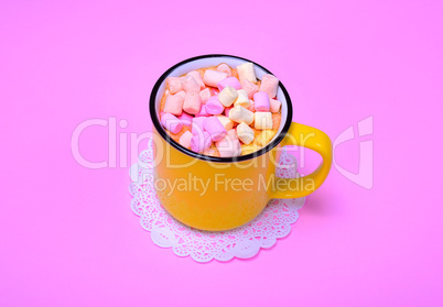 Yellow mug with cocoa and pieces of colorful marshmallow