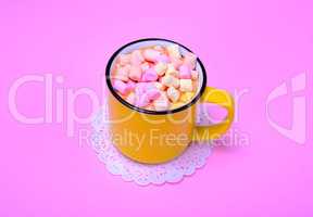 Yellow mug with cocoa and pieces of colorful marshmallow