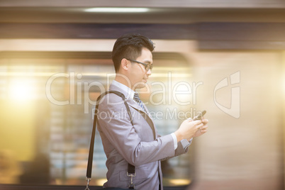 Businessman using smartphone at subway station.