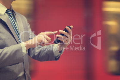 Businessman using smartphone at train station.