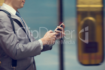 Business man using smart phone at train station.
