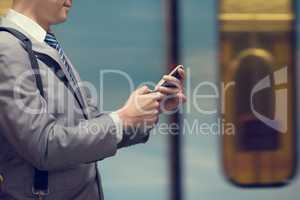 Business man using smart phone at train station.