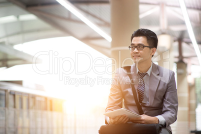 Businessman using tablet pc at train station.