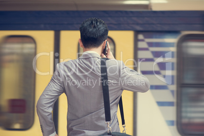 Businessman calling on phone at train station.