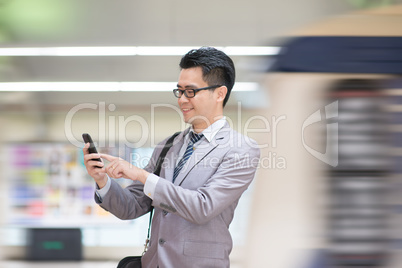Businessman using smartphone at subway.