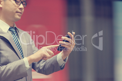 Business man using smartphone at train station.