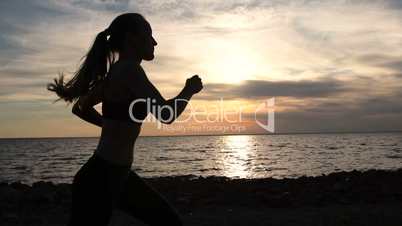 Young fitness woman jogging on seaside at sunset