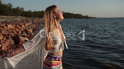 Happy carefree woman enjoying sunset on the beach