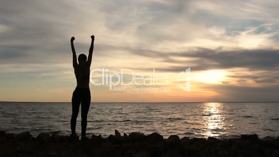 Woman cheering celebrating success at beach sunset