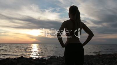 Young slim lady in sports clothes enjoying sunset