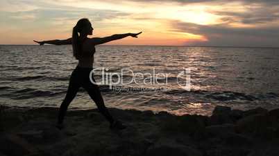 Slim woman exercising yoga warrior pose on beach