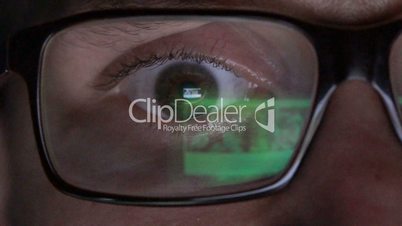 Closeup man's eye in glasses works on laptop at night