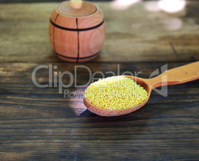 Millet cereals in a wooden spoon on a wooden table