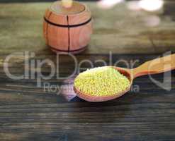 Millet cereals in a wooden spoon on a wooden table