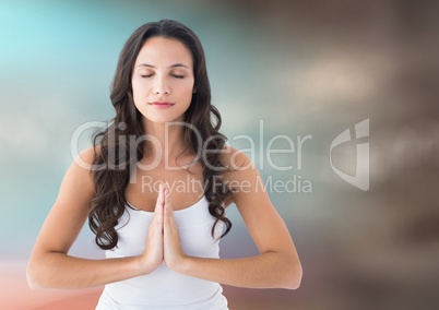 Woman meditating against blurry blue and brown background