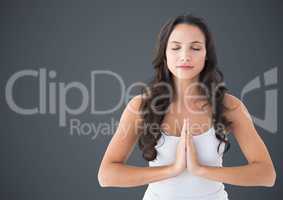Woman meditating against grey background