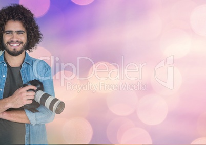 Smiling Photographer holding a camera against glowing background