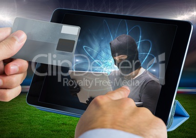 Close up of hand touching a tablet with hacker and holding credit card