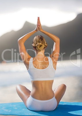 Back of woman meditating on beach