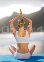Back of woman meditating on beach