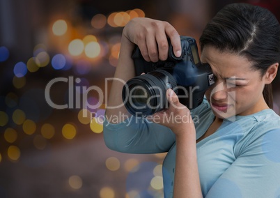 young photographer taking a photo. Blurred city lights at night behind