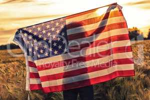 Silhouette of Young Woman Holding USA Flag in Field at Sunset