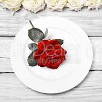 White round plate with a bud of a red rose