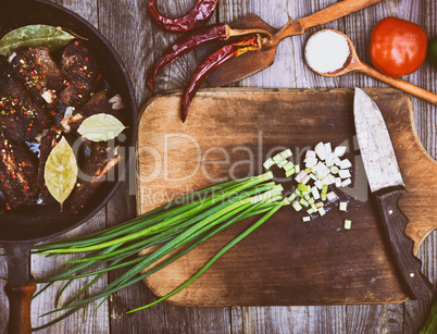 Leaves of green onion on a kitchen board with a knife