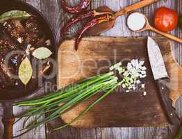 Leaves of green onion on a kitchen board with a knife