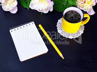 Empty notebook and yellow mug with hot coffee