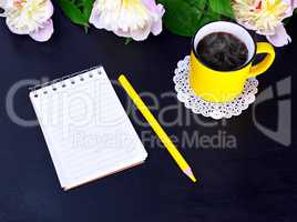Empty notebook and yellow mug with hot coffee