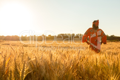 African woman in traditional clothes standing in a field of crop