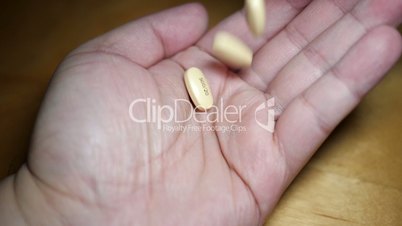 Slow motion of man pouring pills on hand