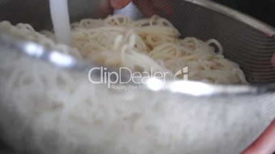 Slow motion of woman draining cooked noodles