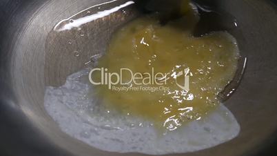 Slow motion of woman pouring egg into frying pan
