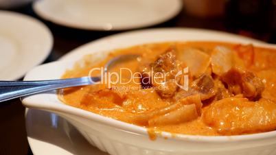 Motion of people stirring curry chicken by spoon on table inside Chinese restaurant