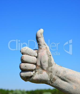 Male finger lifted up against the blue sky, an approving gesture